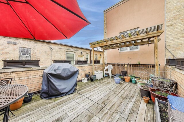 wooden terrace with area for grilling and a pergola