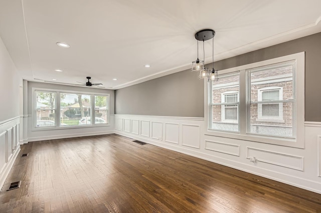 unfurnished dining area featuring wainscoting, ceiling fan, a decorative wall, and visible vents