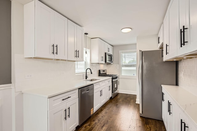 kitchen with a sink, white cabinetry, backsplash, light countertops, and appliances with stainless steel finishes