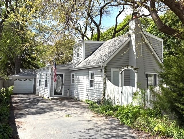 view of front of property featuring driveway, a chimney, and roof with shingles