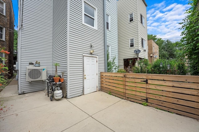 view of side of home with a patio, ac unit, fence, and a gate