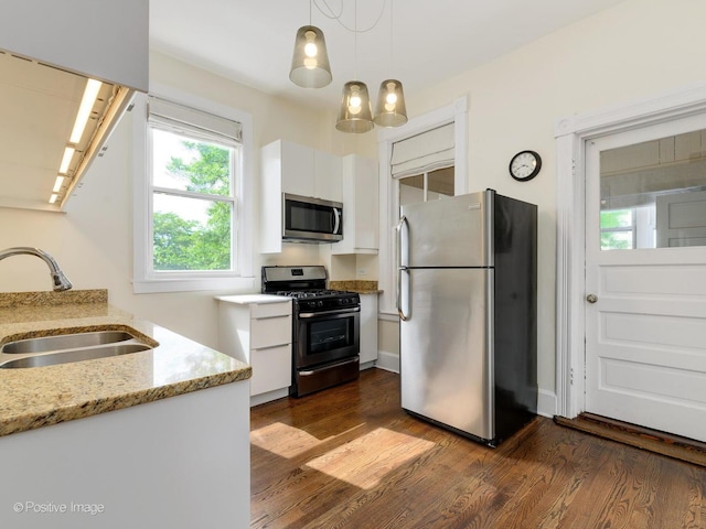 2426 W Mclean Ave, Chicago, IL 60647 - kitchen featuring appliances with stainless steel finishes, a sink, white cabinets, dark wood finished floors, and decorative light fixtures