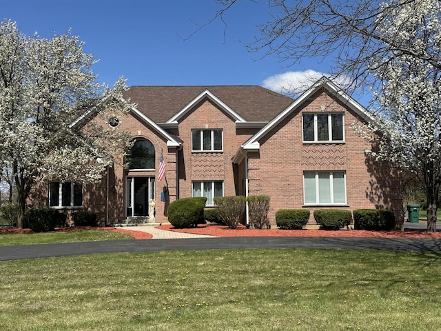 traditional-style home featuring brick siding and a front yard