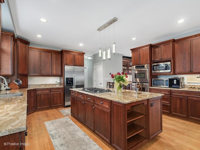 kitchen with a sink, open shelves, stainless steel appliances, a kitchen island with sink, and light wood-type flooring