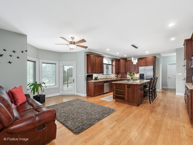 kitchen with light wood finished floors, appliances with stainless steel finishes, a ceiling fan, and open floor plan