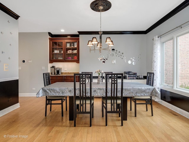 dining room featuring a chandelier, light wood-style flooring, baseboards, and ornamental molding