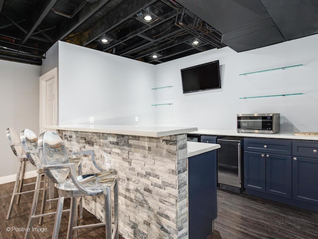 bar featuring stainless steel microwave, refrigerator, and dark wood-style floors