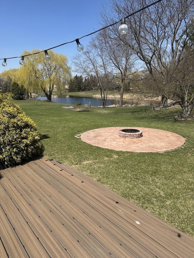 wooden deck featuring a water view, a yard, a patio, and a fire pit