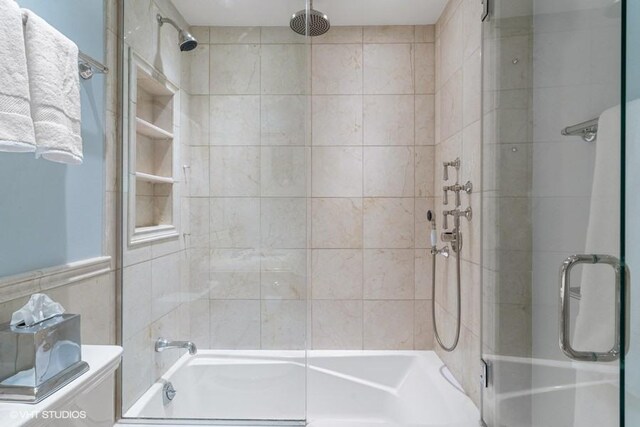 bathroom with bath / shower combo with glass door and toilet