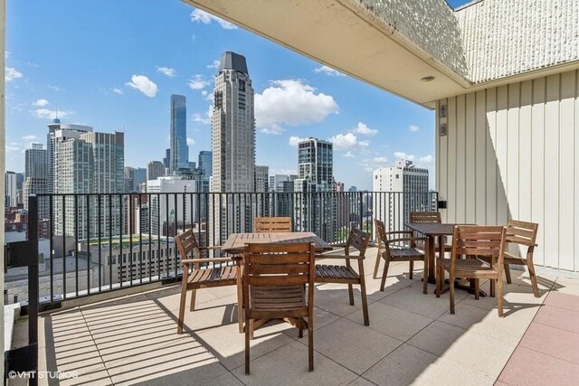 balcony with outdoor dining area and a skyline view
