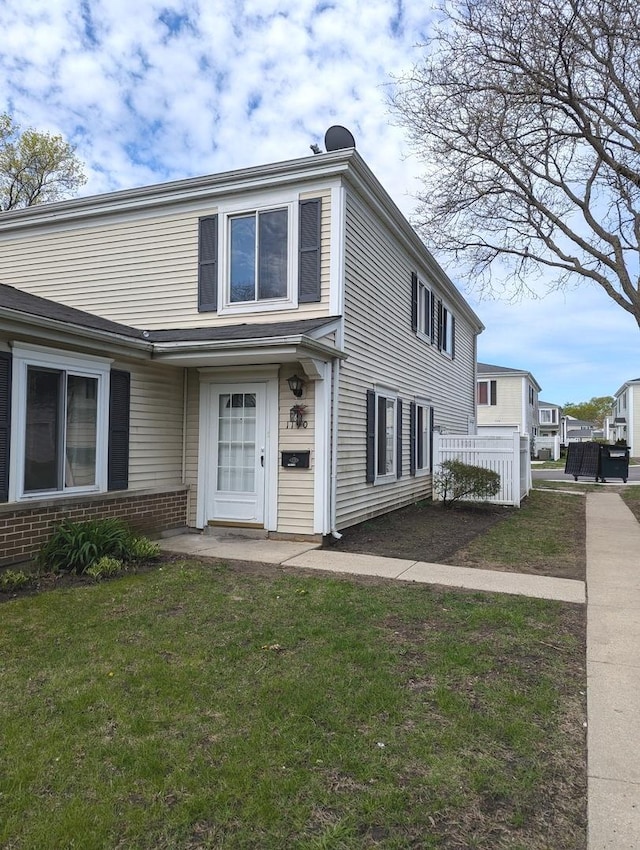 view of front facade featuring fence, a front lawn, and brick siding