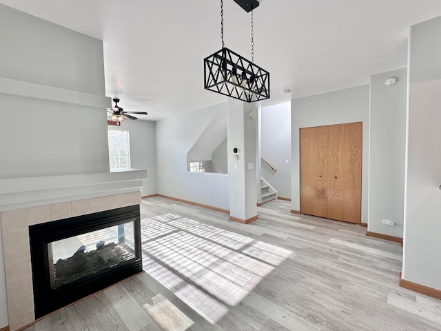 2278 Twilight Dr, Aurora, IL 60503 - unfurnished living room with wood finished floors, a tiled fireplace, stairway, baseboards, and ceiling fan