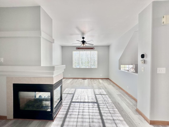 2278 Twilight Dr, Aurora, IL 60503 - unfurnished living room featuring ceiling fan, light wood-style flooring, a tiled fireplace, and a healthy amount of sunlight