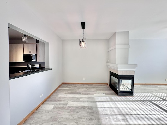2278 Twilight Dr, Aurora, IL 60503 - unfurnished dining area with light wood finished floors, a tiled fireplace, baseboards, and a sink
