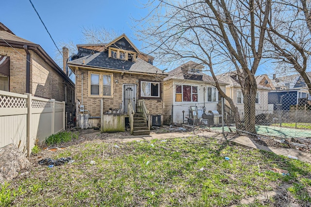 7002 S Hermitage Ave, Chicago, IL 60636 - rear view of house featuring brick siding, roof with shingles, and fence