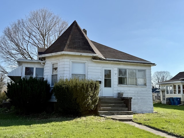 view of front of home with a chimney, a front yard, roof with shingles, and entry steps
