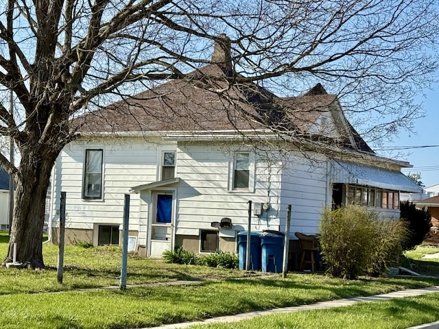 rear view of house with a chimney and a lawn