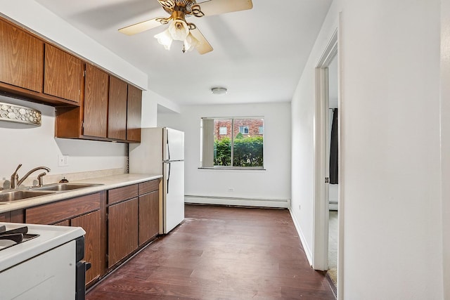 kitchen featuring a sink, white appliances, dark wood finished floors, ceiling fan, and baseboard heating
