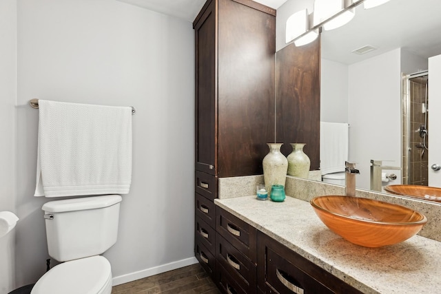 bathroom with toilet, vanity, visible vents, an enclosed shower, and baseboards