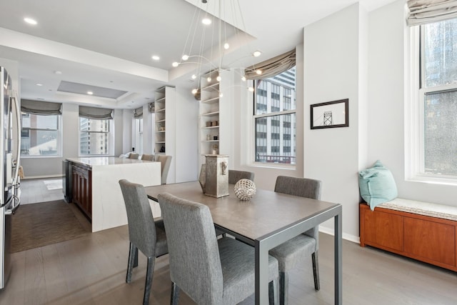 dining room featuring a tray ceiling, light wood finished floors, baseboards, and recessed lighting