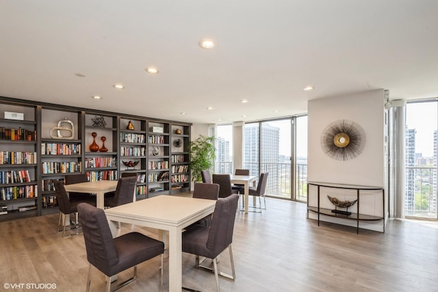 dining area with a wall of windows, light wood-style floors, and recessed lighting