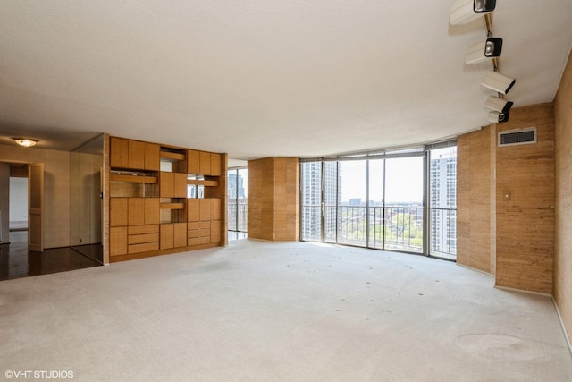 unfurnished living room featuring light colored carpet, plenty of natural light, and expansive windows