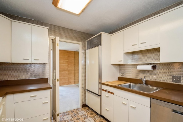 kitchen featuring a sink, stainless steel dishwasher, built in fridge, tasteful backsplash, and white cabinetry