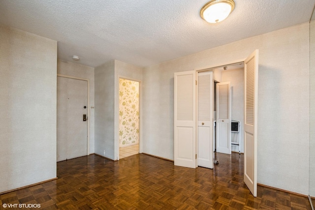unfurnished room featuring a textured ceiling, baseboards, and a smoke detector