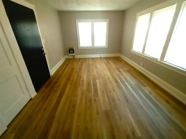unfurnished room with baseboards, a healthy amount of sunlight, and wood finished floors
