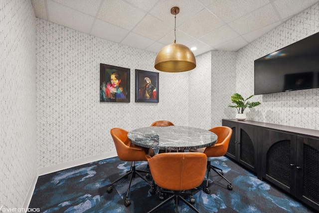 carpeted dining room with a drop ceiling and baseboards