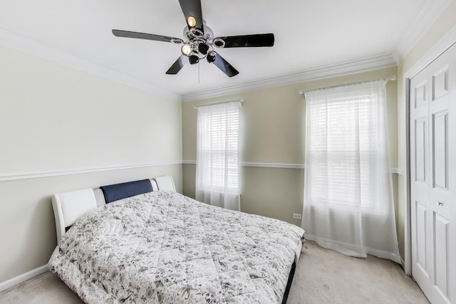 bedroom featuring a closet, crown molding, baseboards, ceiling fan, and light colored carpet