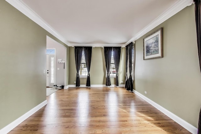 empty room with ornamental molding, baseboards, and wood finished floors