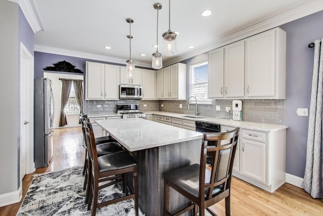 kitchen with ornamental molding, stainless steel appliances, a center island, and a sink
