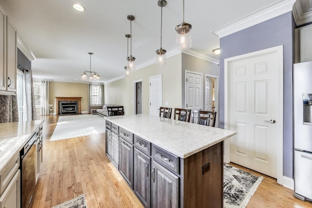 kitchen featuring light stone countertops, a center island, light wood finished floors, crown molding, and a fireplace