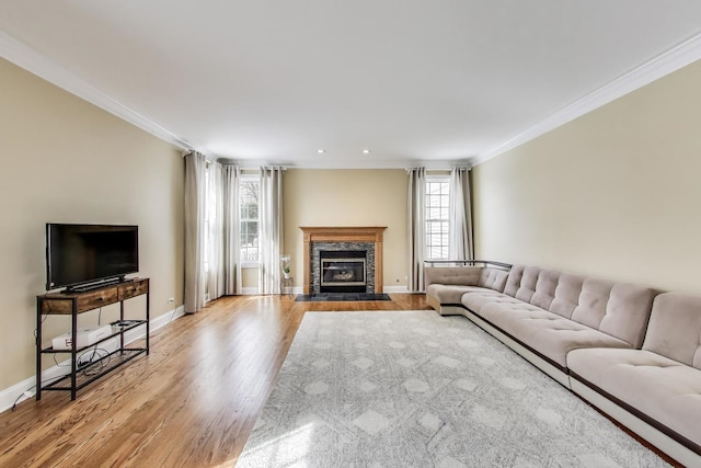living area with wood finished floors, recessed lighting, a fireplace, crown molding, and baseboards