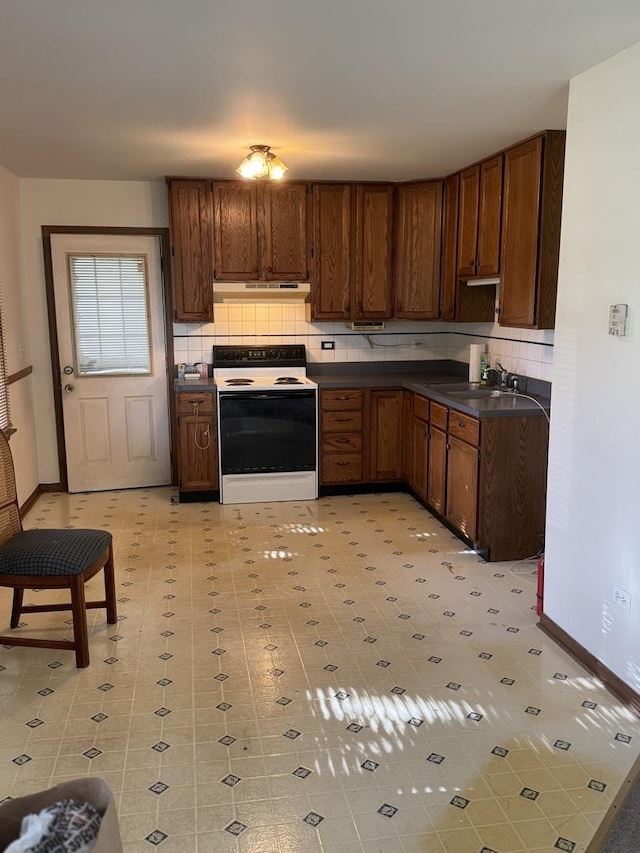 603 Kingston Dr, Romeoville, IL 60446 - kitchen with electric stove, a sink, under cabinet range hood, dark countertops, and decorative backsplash