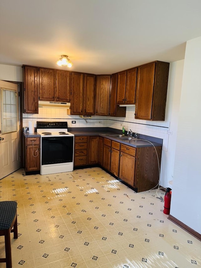 603 Kingston Dr, Romeoville, IL 60446 - kitchen featuring range with electric stovetop, under cabinet range hood, dark countertops, a sink, and tasteful backsplash