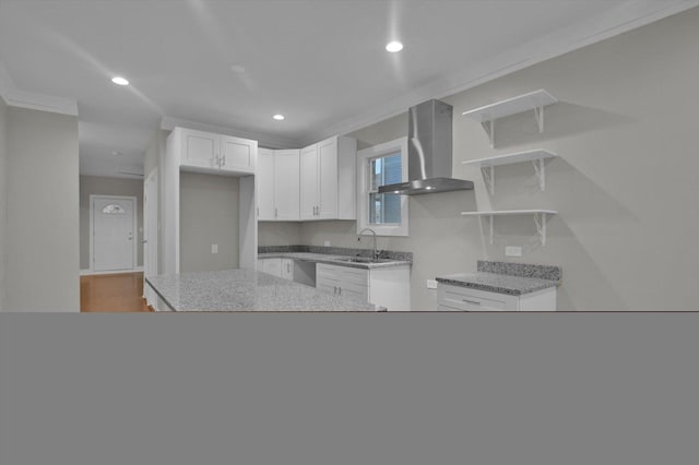 kitchen with a sink, recessed lighting, dishwasher, wall chimney exhaust hood, and white cabinetry