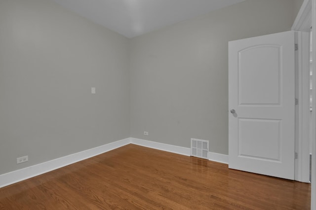 spare room with wood finished floors, visible vents, and baseboards