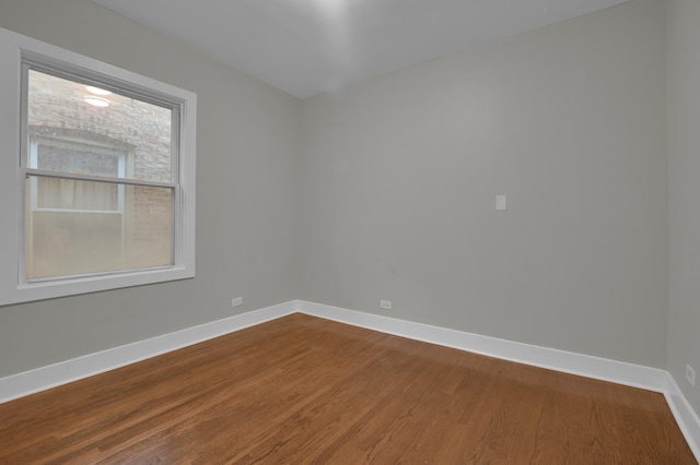 unfurnished room featuring baseboards and dark wood-style floors