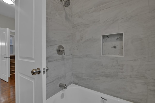 bathroom with washtub / shower combination and wood finished floors