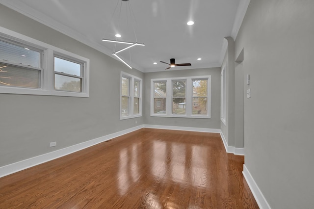 empty room featuring baseboards, ornamental molding, ceiling fan, and wood finished floors