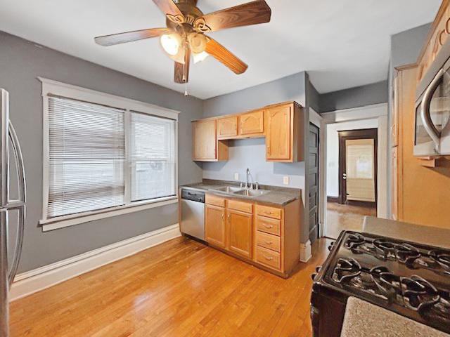 kitchen featuring light wood-style flooring, light brown cabinetry, a sink, stainless steel appliances, and ceiling fan