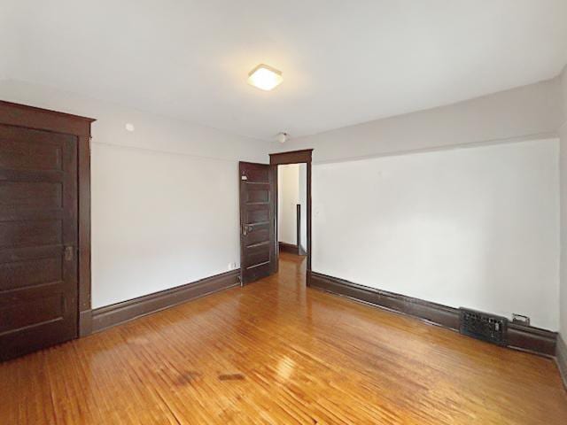 spare room featuring baseboards and wood finished floors