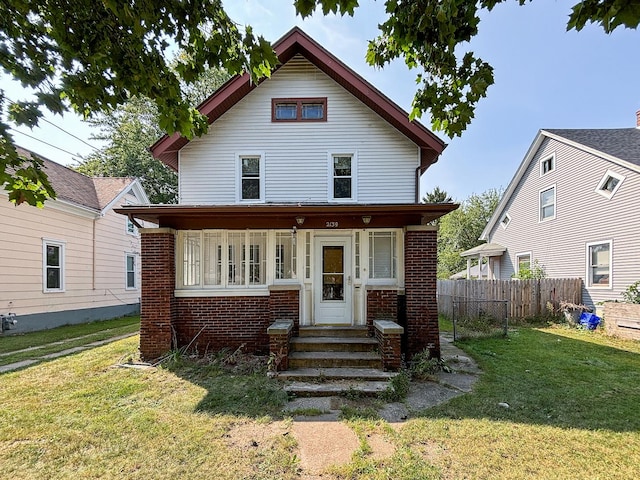 view of front of house with a front yard, brick siding, fence, and entry steps