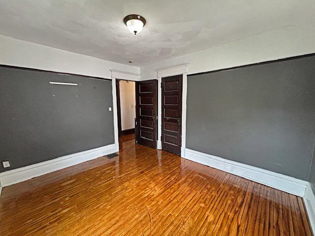 spare room featuring baseboards and wood finished floors