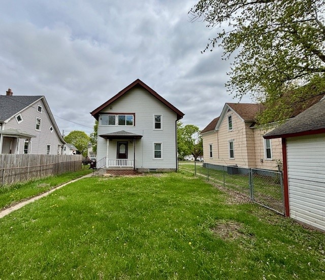 rear view of property with fence and a lawn