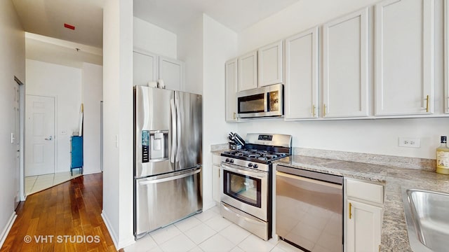 340 W Superior St Unit 1602, Chicago, IL 60654 - kitchen featuring appliances with stainless steel finishes, white cabinetry, light stone counters, a sink, and light wood finished floors