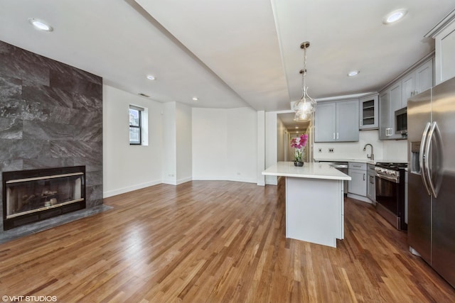 kitchen featuring gray cabinetry, open floor plan, light wood-type flooring, and appliances with stainless steel finishes