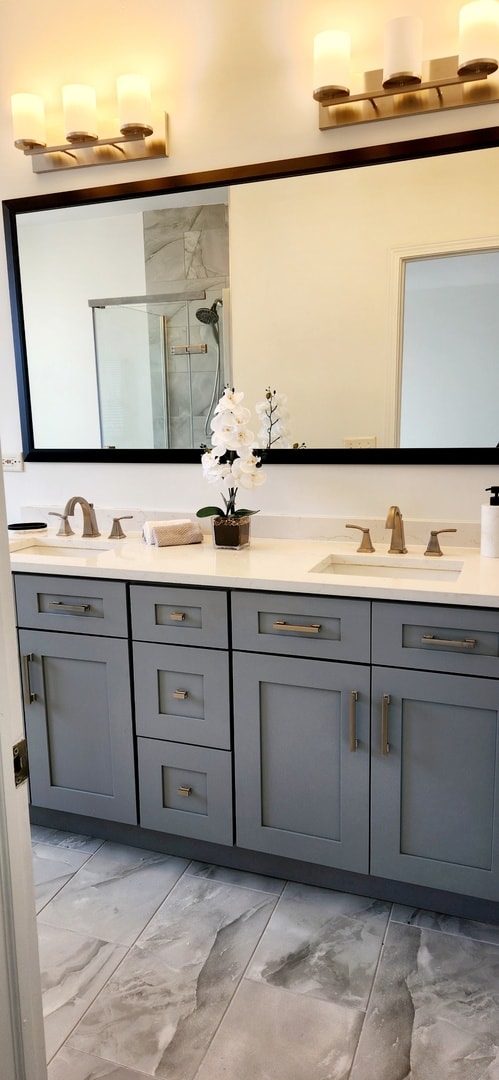 full bath with a stall shower, marble finish floor, double vanity, and a sink